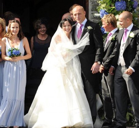 Bret Desmond and Andrea Corr posing for the photograph alongside bridesmaid and groomsmen in front of church